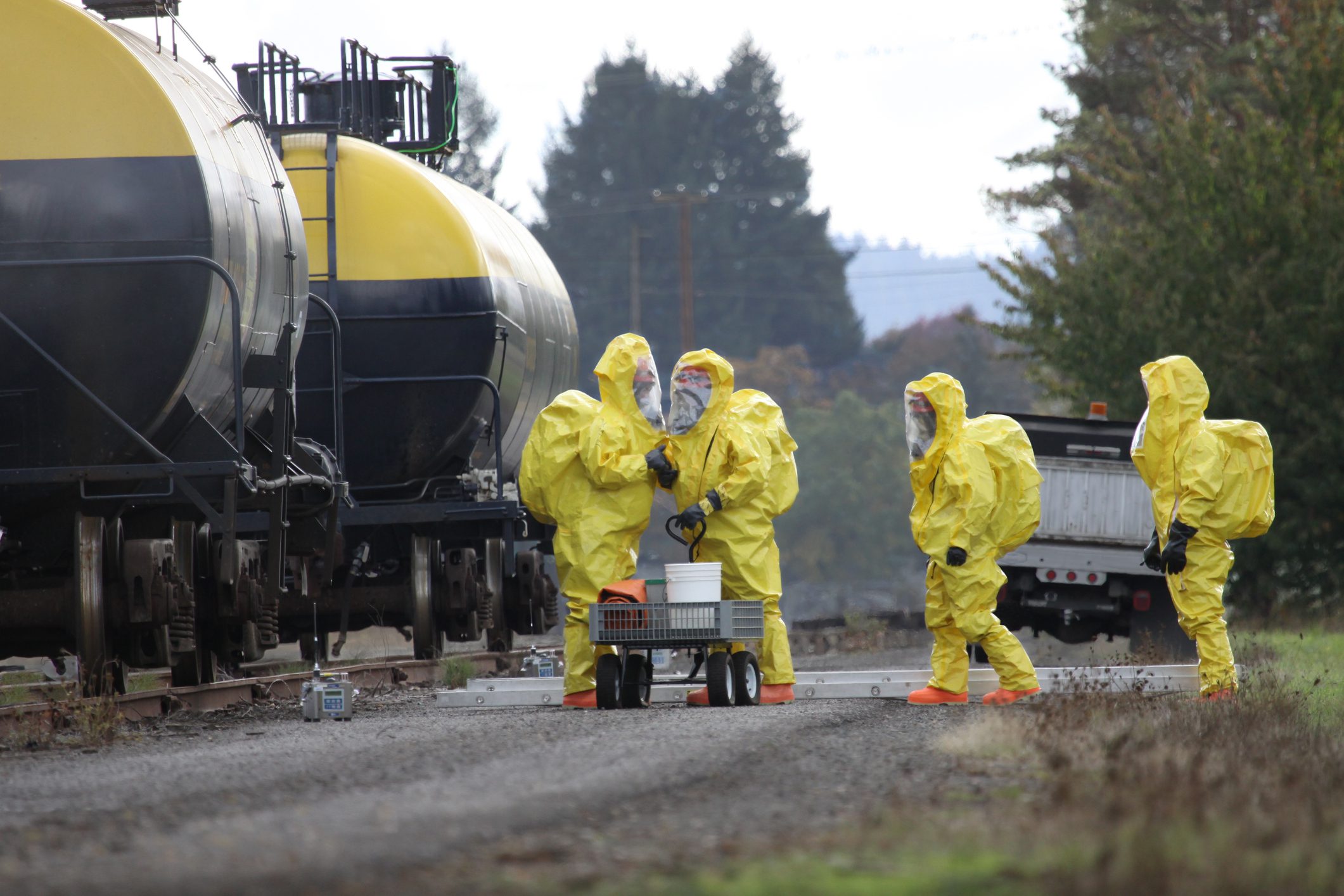 HAZMAT Team Members Discusses Chemical Disaster A group of people in yellow suits near a train.