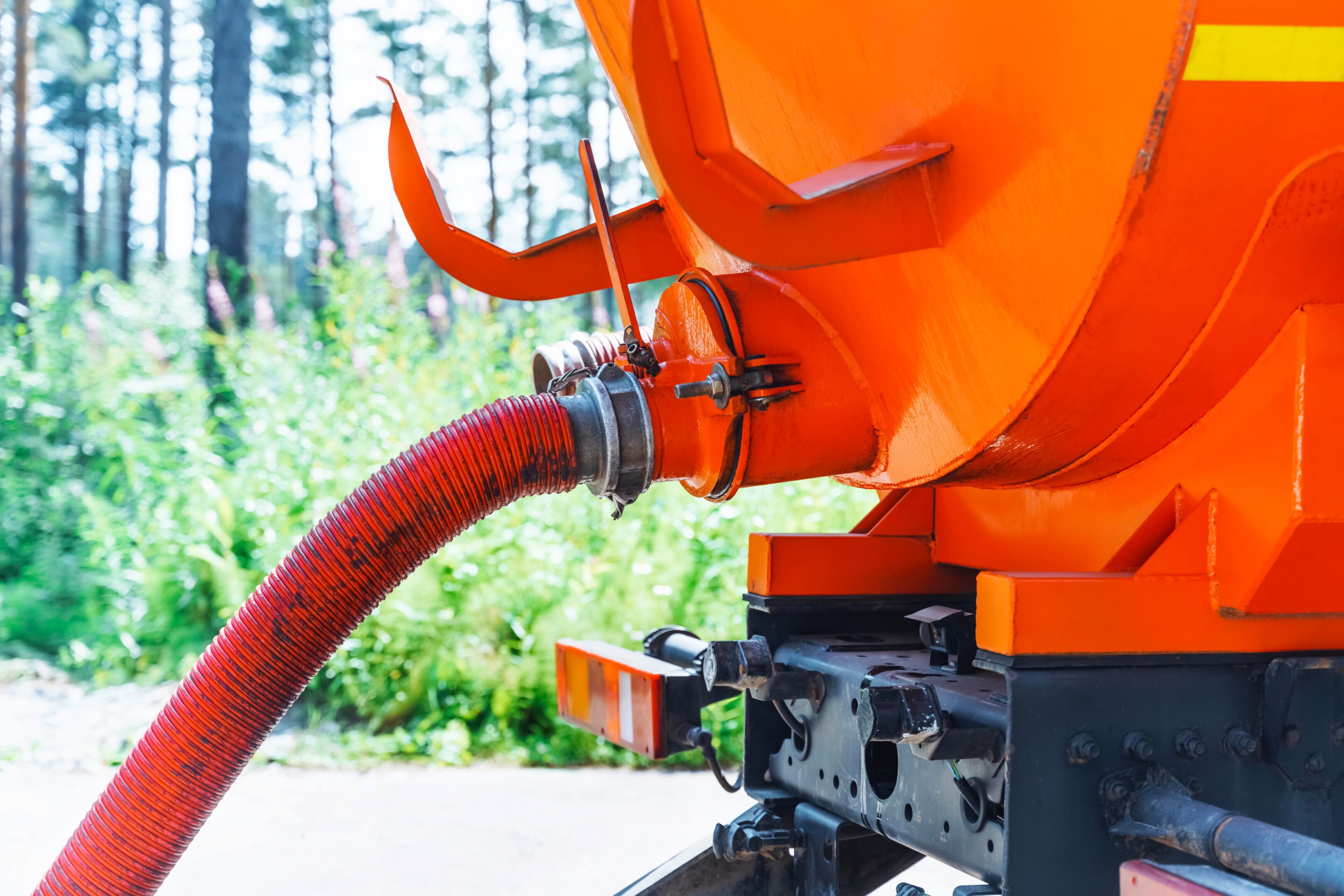 Sewage Tank truck. A close up of the hose on an orange truck.